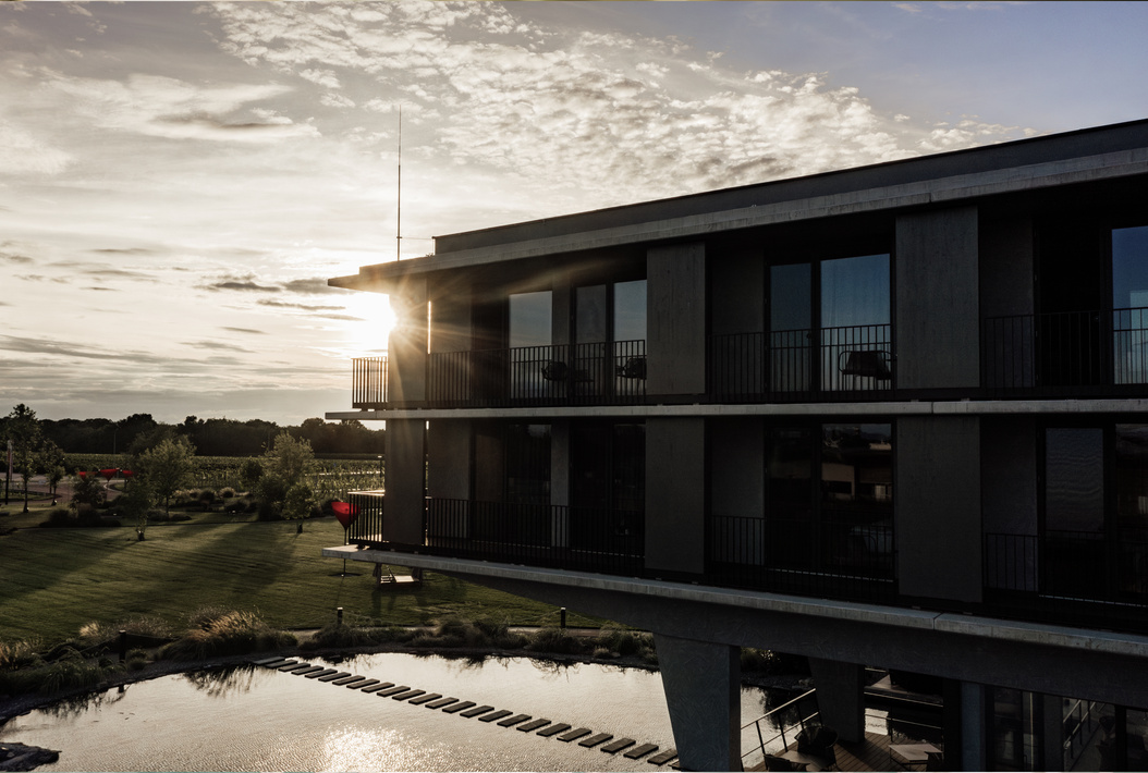 Modernes Gebäude bei Sonnenuntergang mit Blick auf einen Teich und eine gepflegte Grünanlage.