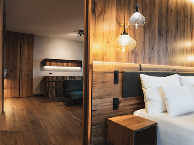 Modernes Hotelzimmer mit holzgetäfelten Wänden, einem Bett mit weißen Kissen und hängenden Pendelleuchten.